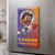 2x3 Rex Uranus Fudge Factory magnet on a stainless steel refrigerator door, featuring Rex the bearded astronaut mascot riding the URANU$ rocket on a purple-to-orange gradient background.