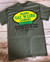 Uranus Gas N Lube T-Shirt in olive green lying flat on a wooden table.