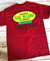 Uranus Gas N Lube T-Shirt in red lying flat on a wooden table.
