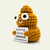 Yellow crocheted Emotional Support Poop holding a Nothing Beats Uranus sign, side angle