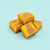 Four squares of Lemon Iced Tea Fudge stacked on a light blue background