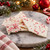 White chocolate peppermint bark pieces on a marble board with candy canes, pine branches and red Christmas ornaments