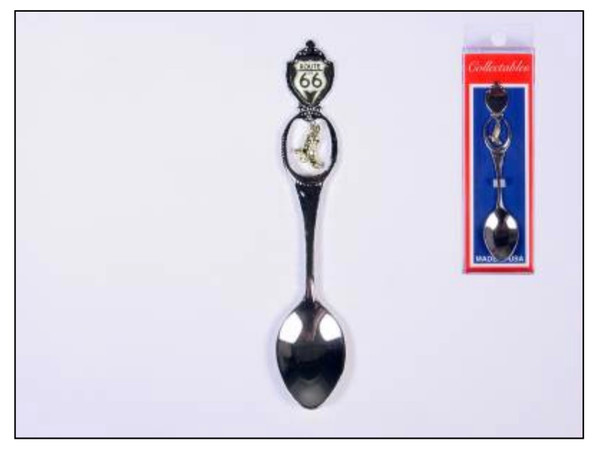 A silver Route 66 souvenir spoon featuring a black highway shield and gold cowboy boot on the handle next to its retail packaging