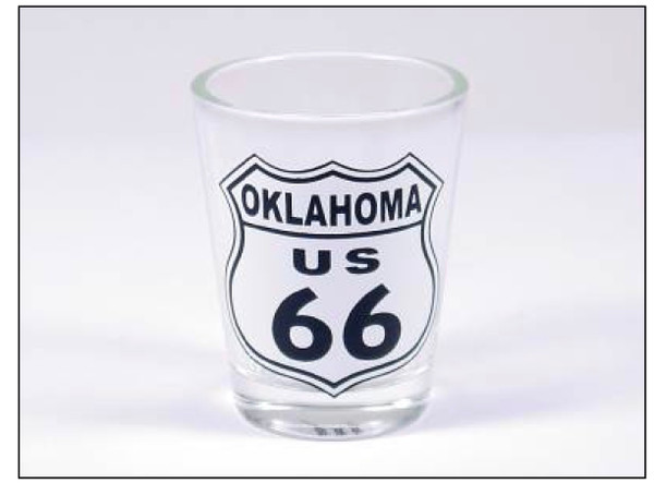 A clear glass souvenir shot glass featuring a black and white Oklahoma US 66 highway shield design