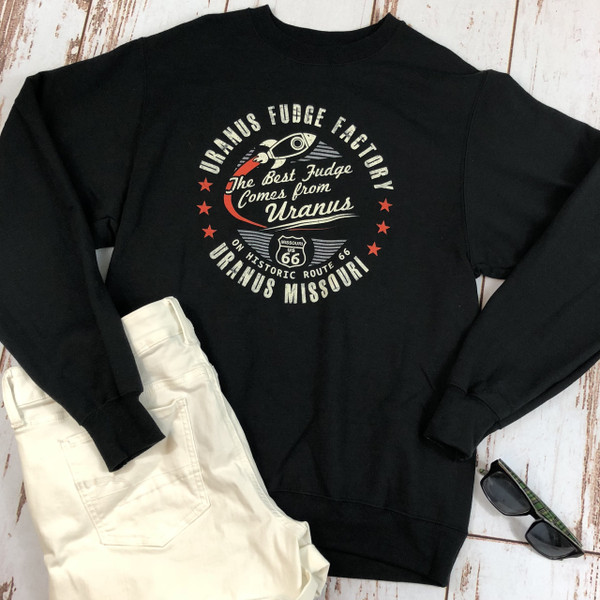 Flat lay of black Uranus Fudge Factory crewneck sweatshirt with vintage rocket graphic.