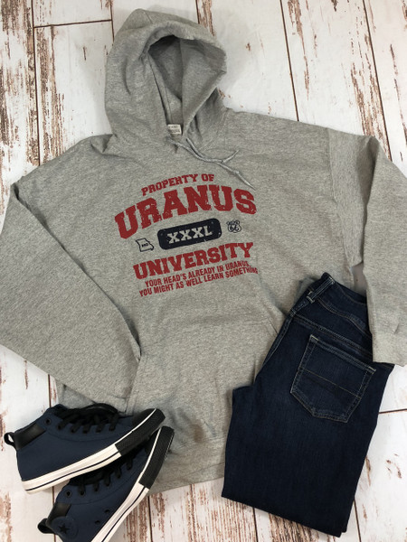 A flat lay of a casual outfit featuring a heather gray pullover hoodie with a "Property of Uranus University" graphic in distressed red and navy ink.