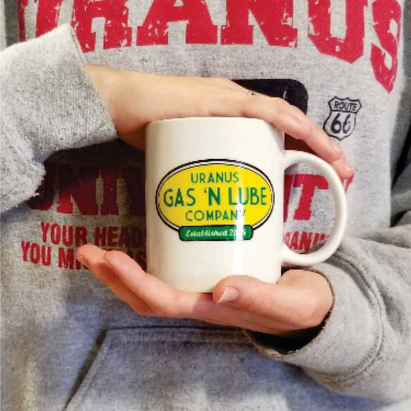 A person holding a white Uranus Gas 'N Lube Company novelty mug from Uranus Fudge Factory.