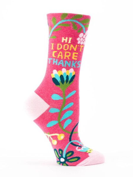 A single bright pink crew sock displayed against a plain white background. The sock features pale pink accents on the toe and heel. It is decorated with a vibrant, retro floral pattern of stylized vines and large flowers in bright teal, green, yellow, dark blue, and white. Knit into the upper ankle, sandwiched between the colorful floral elements, is the bold, stacked text: "HI" and "I DON'T CARE" in yellow, followed by "THANKS" in teal.