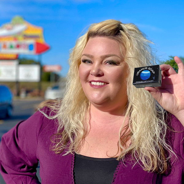 Miss Tiffany holding a bar of Uranus Soap outdoors with the Uranus Fudge Factory sign in the background