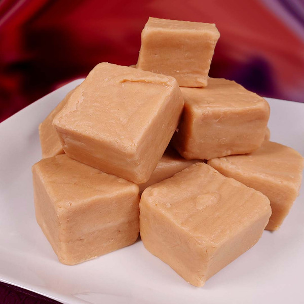 A stack of creamy peanut butter fudge cubes on a plate from Uranus Fudge Factory.