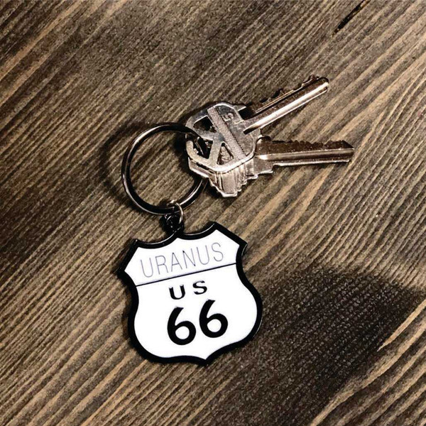 Keys attached to a Uranus Route 66 shield novelty keychain on a rustic wooden table background Uranus Fudge Factory.