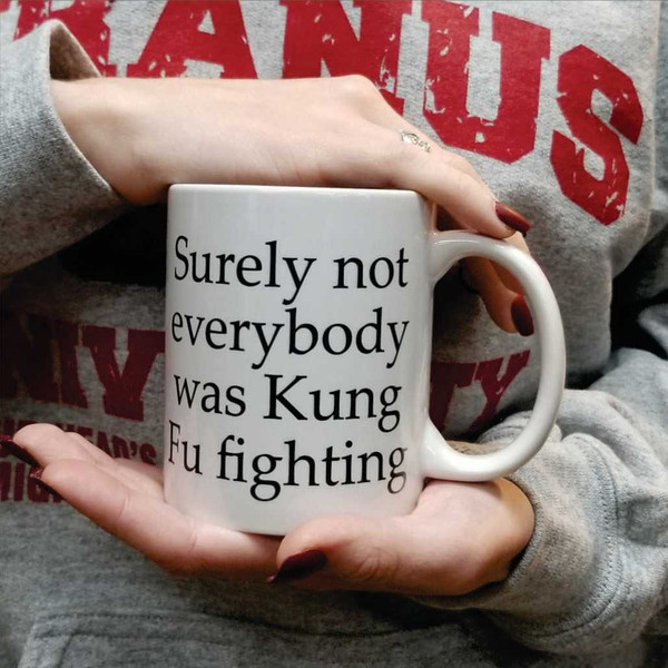 Woman holding Surely Not Everybody Was Kung Fu Fighting coffee mug novelty gift.