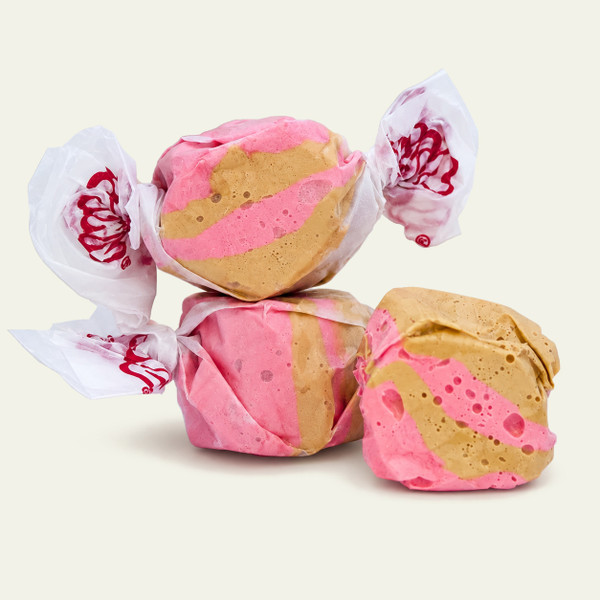 Brown and pink maple bacon gourmet salt water taffy pieces stacked against a plain white background