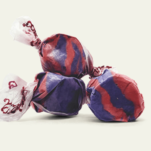Three colorful wrapped saltwater Tropical Punch taffy candies stacked together on a plain white background by Uranus Fudge Factory.
