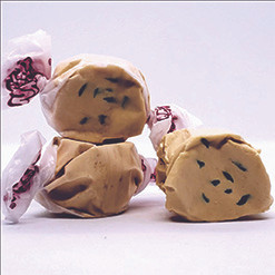 Three colorful wrapped Blueberry Muffin saltwater taffy candies stacked together on a plain white background by Uranus Fudge Factory.
