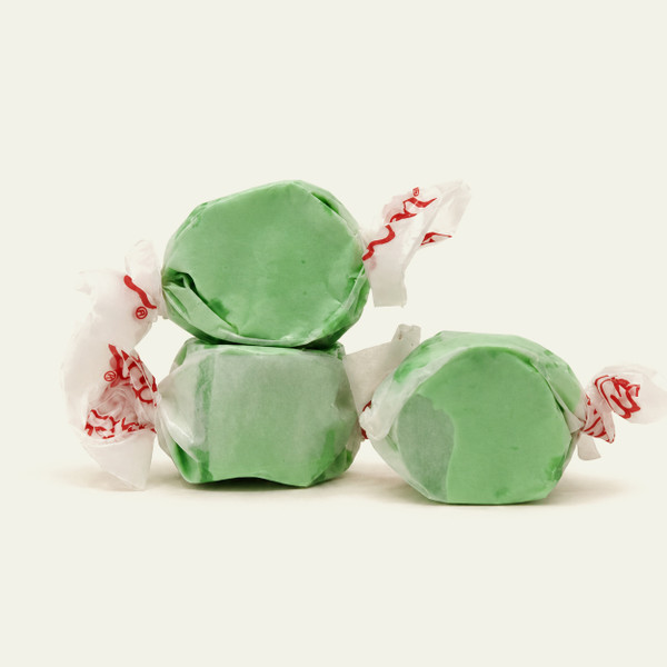 Three pieces of green salt water taffy candies wrapped in wax paper.