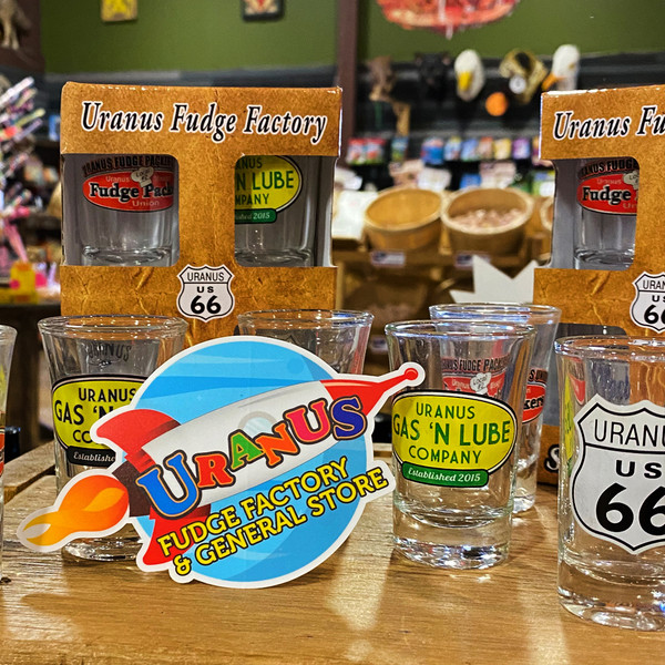 Round space rocket cartoon souvenir sticker displayed with clear shot glasses from Uranus Fudge Factory