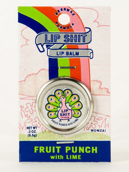 A round silver lip balm tin attached to a retro-illustrated cardboard backing against a plain white background. The packaging features a colorful rainbow and a banner reading the cheeky brand name "LIP SHIT", while the tin showcases a pink cartoon peacock and text matching the flavor banner at the bottom: "FRUIT PUNCH with LIME".