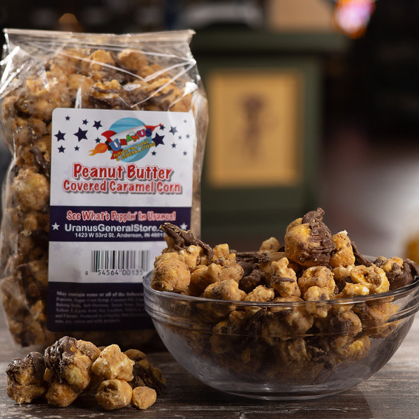 Peanut butter caramel corn bag next to a full glass bowl with a blurred background by Uranus Fudge Factory.