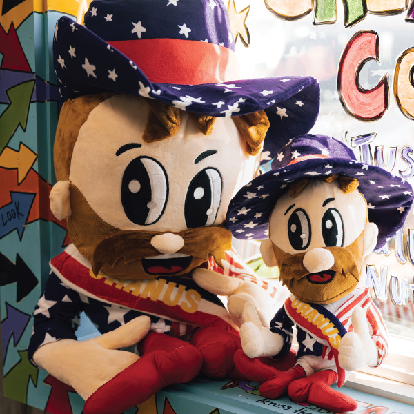 Two different sized Rex Uranus mascot plush toys sitting on a window sill inside Uranus Fudge Factory.