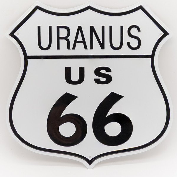 A white metal souvenir sign cut into the shape of a US 66 highway shield with Uranus text at the top