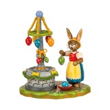 Mrs. Rabbit is decorating the village fountain with colorful ribbons and eggs for Easter.