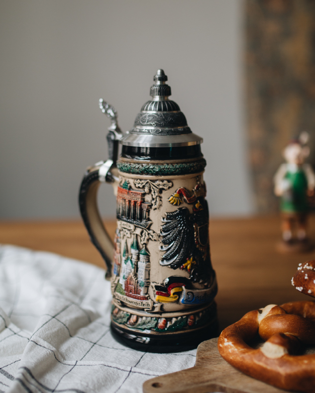 Photo of traditional German beer stein on wood table with white cloth and German pretzel