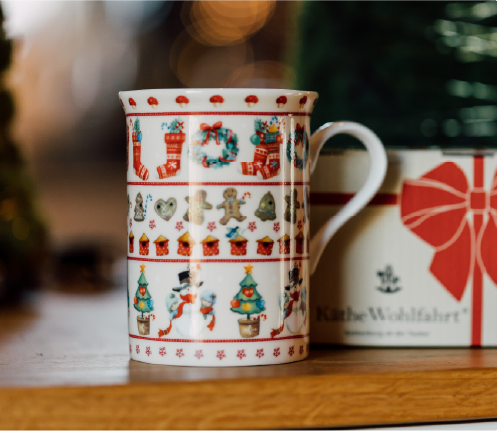 Easter themed pyramid with flower tealight candle holders and three rabbits on a small table with a coffee pot, cup and plate with pastry and a vase with daffodils. 