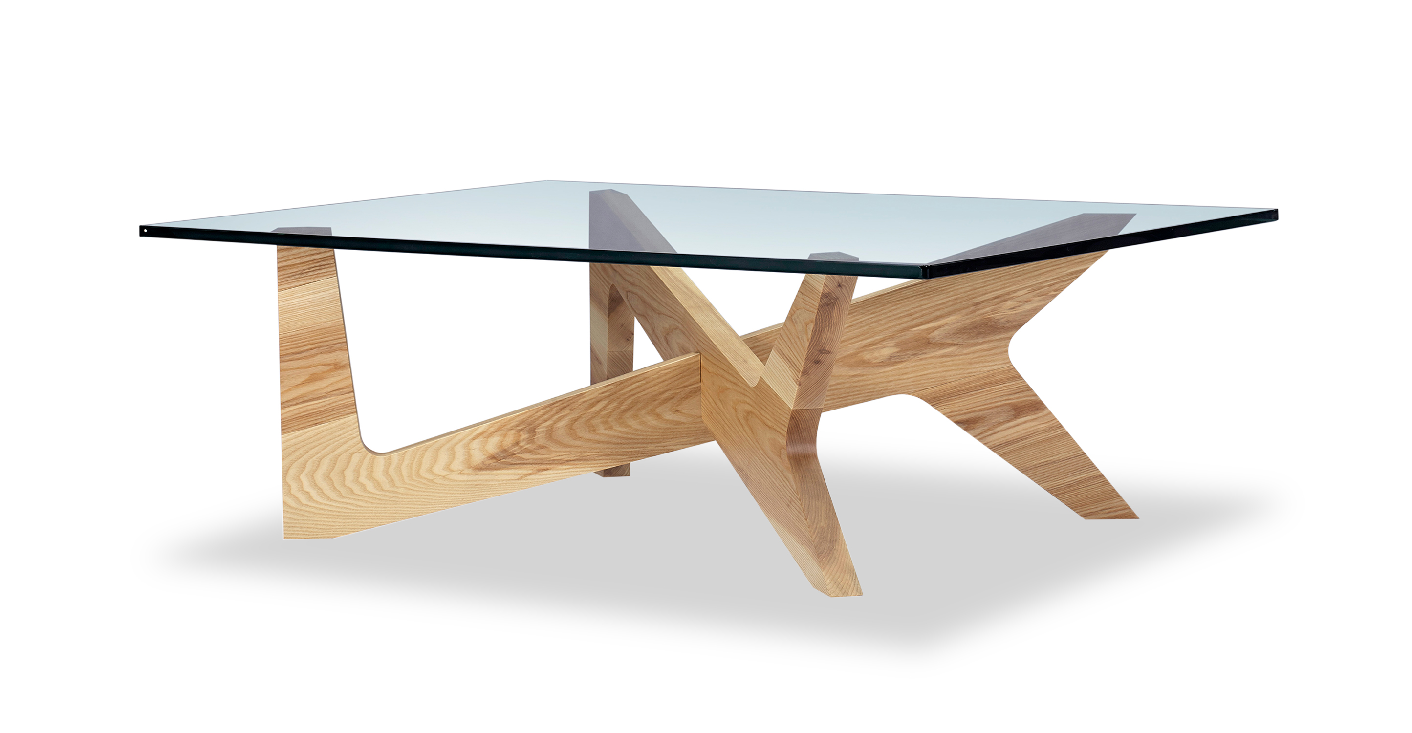 The Cross coffee table has a natural wood base and a glass top. The base supports the table from 4 points. There are two base pieces that cross each other in the center. Each base piece's shape looks like a Y on one end and an L on the other end. The vibe is modern wooden sculpture-esque, high-end design.