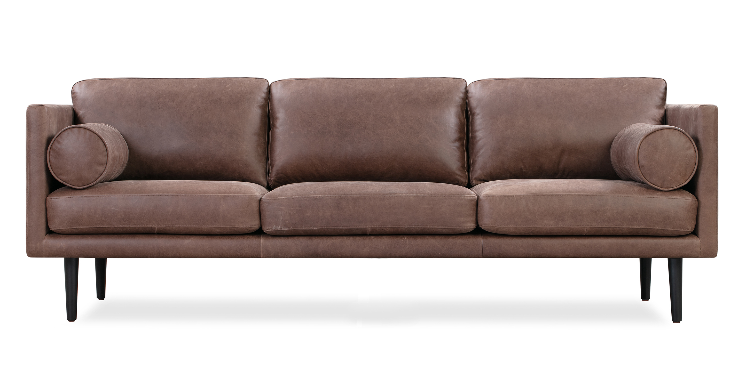 The Spectre Mocha Brown Leather is a timeless contemporary sofa that is 100% upholstered. It features a cohesive design with both the base frame and arms sharing the same thickness, resulting in a harmonious and consistent look. The sofa's three seat and back cushions are removable and strike a balance between being well-cushioned and not overly stuffed. To further enhance comfort, the Spectre includes two bolster pillows positioned on either side of the arm. The sofa is raised by tapered wooden legs.