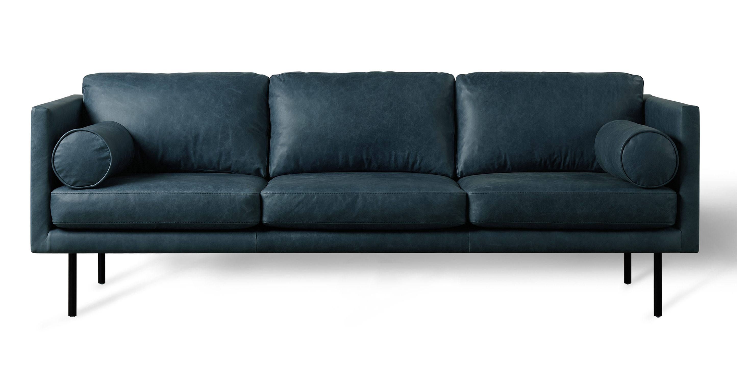 The Spectre Midnight Blue Leather is a timeless contemporary sofa that is 100% upholstered. It features a cohesive design with both the base frame and arms sharing the same thickness, resulting in a harmonious and consistent look. The sofa's three seat and back cushions are removable and strike a balance between being well-cushioned and not overly stuffed. To further enhance comfort, the Spectre includes two bolster pillows positioned on either side of the arm. The sofa is raised by tapered wooden legs.