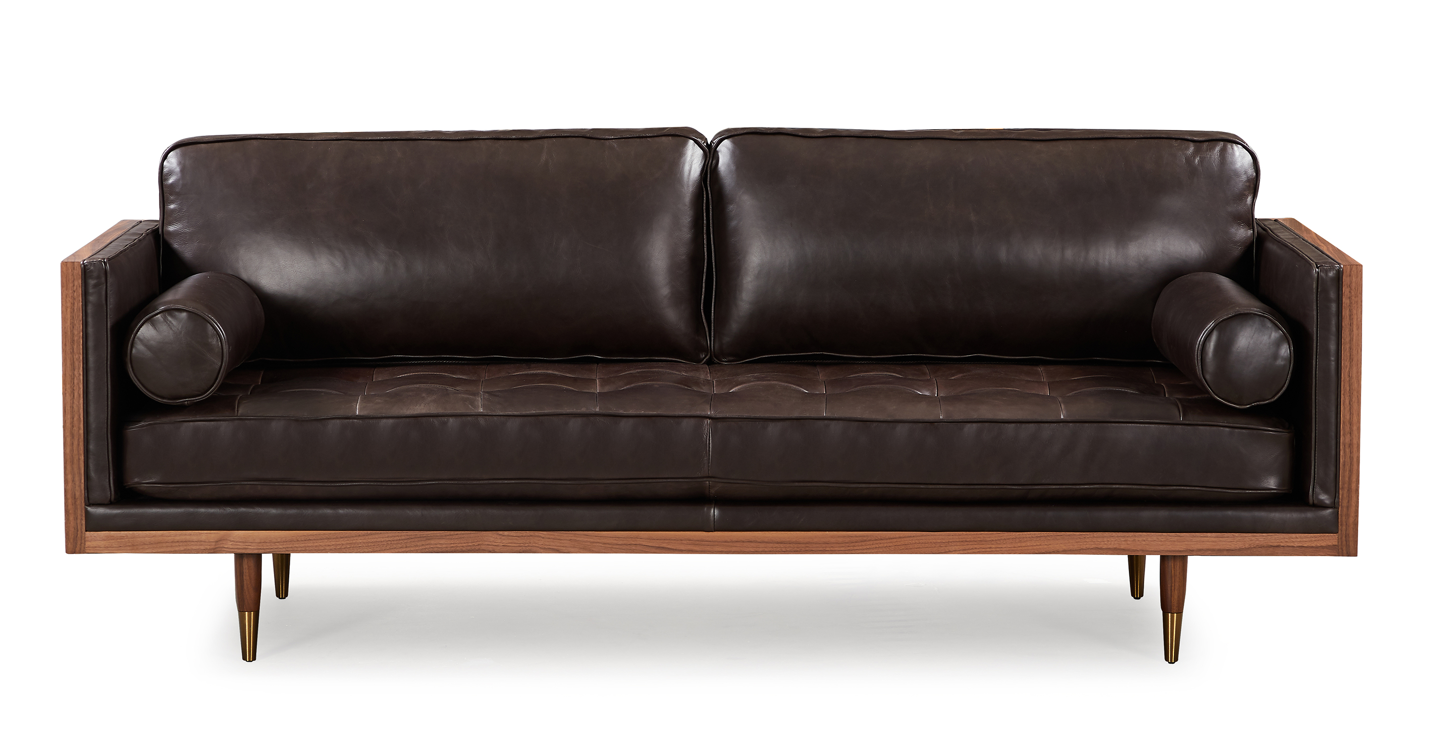 Image shows Woodrow Skandi saddle Black leather is a walnut wood wrapped sofa. The top and  of the arms and back are all walnut wood rectangles, creating a box shape. The interior arms are affixed and smooth. The back cushions are smooth and removable. The seat cushion is tufted and removable. There are two round bolsters included with the sofa, which contrast nicely to the squared and rectangle angles of the love seat shape and other cushions. The four legs are matching walnut wood and tapered. 