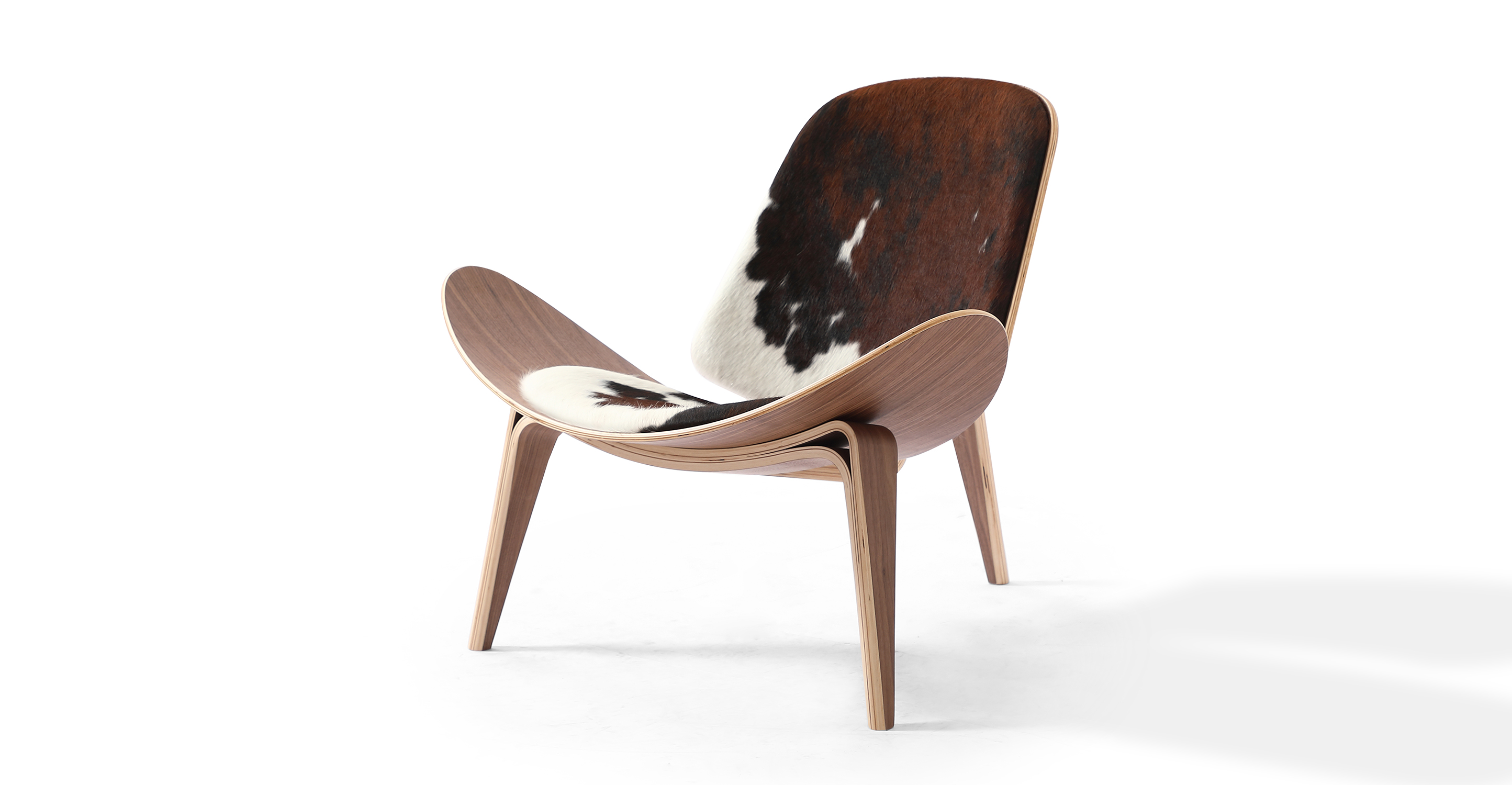 Image shows right facing view of Mid-Century Modern Tripod Lounge Chair in Black/Brown/White authentic cowhide. The chair has Walnut frame and legs. The chair has fixed cushions. The chair's seat curves upward on the sides.