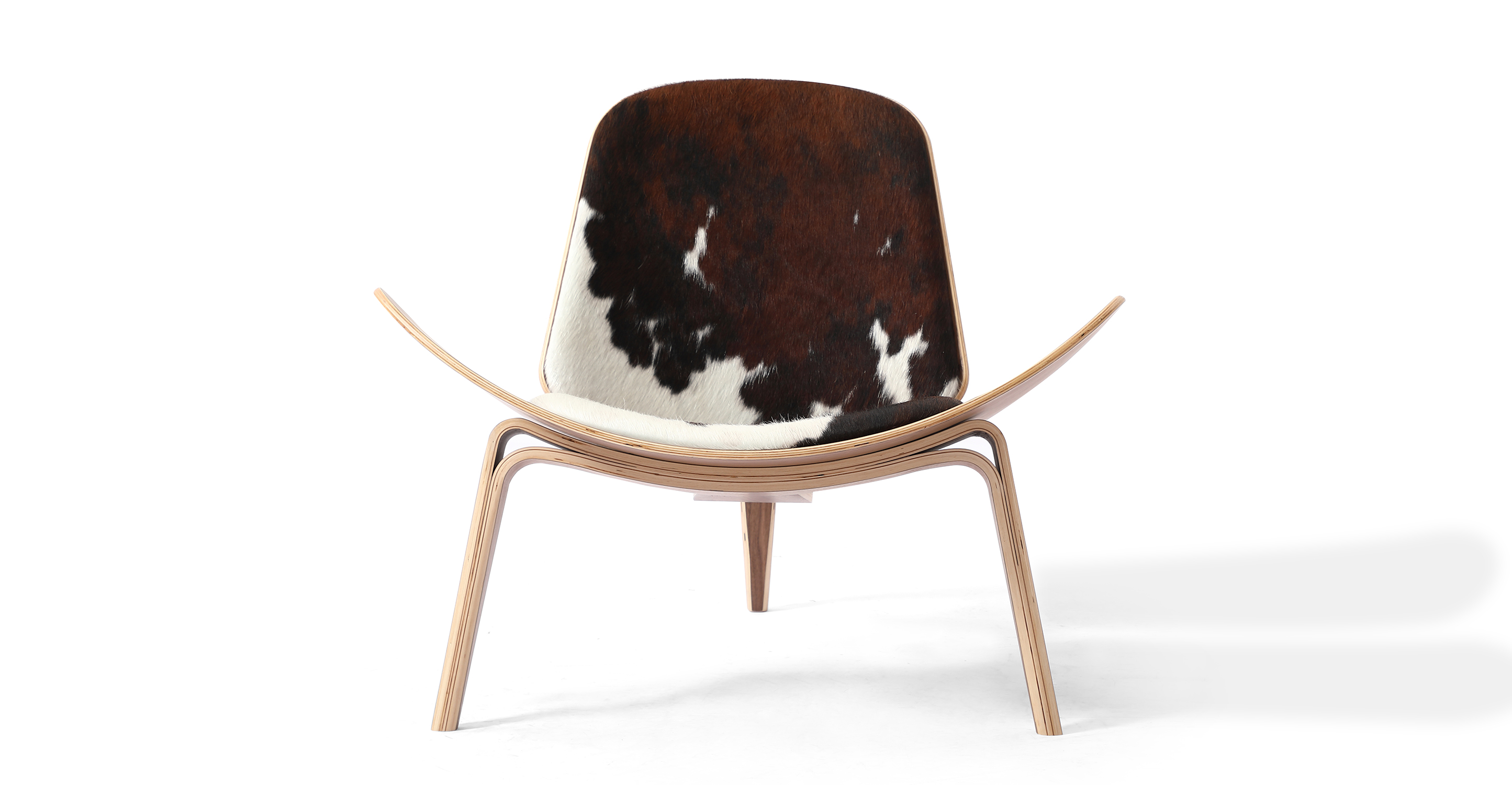 Tripod Lounge Chair in cowhide ( black, brown, white mix ) upholstery. The chair has Walnut frame and legs. The chair has fixed cushions. The chair's seat curves upward on the sides with visible layer bent plywood. The plywood is also  use and the back and the three bent plywood legs.