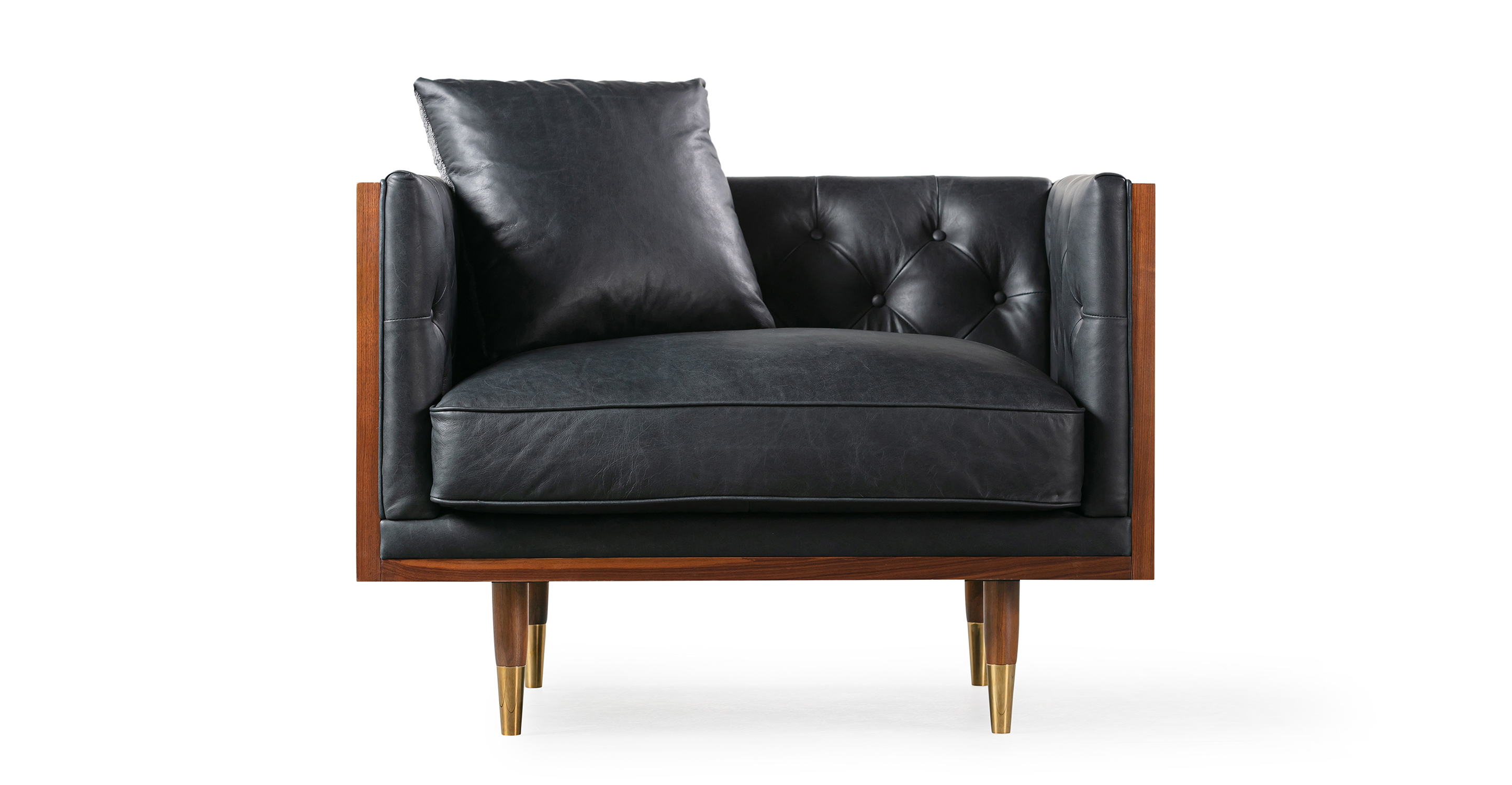 Woodrow Neo Milano Black leather is a walnut wood wrapped chair. The top and of the arms and back are all walnut wood rectangles, creating a box shape. The interior of the chair back and seat are affixed and tufted cushions. There is a matching throw pillow. The seat cushion is smooth and removable. The legs are matching walnut wood, tapered, and brass tipped.