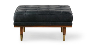 Image shows front facing picture of Mid-Century Modern Woodrow Box Ottoman in Milano Black Leather. Frame and legs are walnut wood. Legs are brass tipped walnut wood. The cushion is button tufted. 