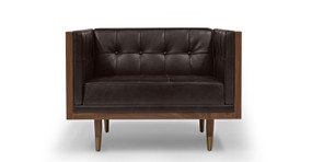 Image shows front picture of Kardiel's Mid-Century Modern Woodrow Box walnut wood wrapped chair in Saddle Black Leather. The boxy shaped chair has button tufted back, seat and side cushions. The chair's legs are brass tipped walnut wood. 