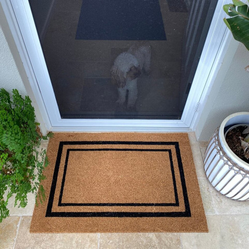 Coir Mat at front door with black double border styled with plants and cavoodle