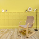 Berkeley Shaker MDF Half Wall Panelling Kit, interior decorative wall paneling with a bright yellow color, installed on a wall behind a wooden lounge chair and a tall floor lamp in a modern home setting.