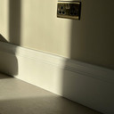 Skirting World Antique 2 MDF Skirting Board, a close-up view of a white MDF skirting board with decorative grooves installation at the base of a wall.