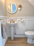 Skirting World Astragal MDF Panel Moulding, interior bathroom with white wainscoting, wall-mounted floral decor, and a mirror above a pedestal sink.