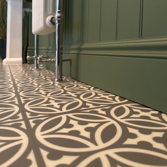 Skirting World 330 MDF Skirting Board, close-up view of green skirting board installed at the bottom of a wall with patterned floor tiles.
