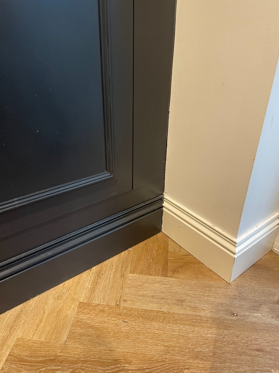 Black skirting board meeting white skirting board at a corner showing colour contrast