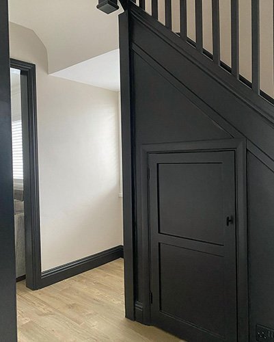 Black painted skirting board and staircase panelling contrasting with white walls