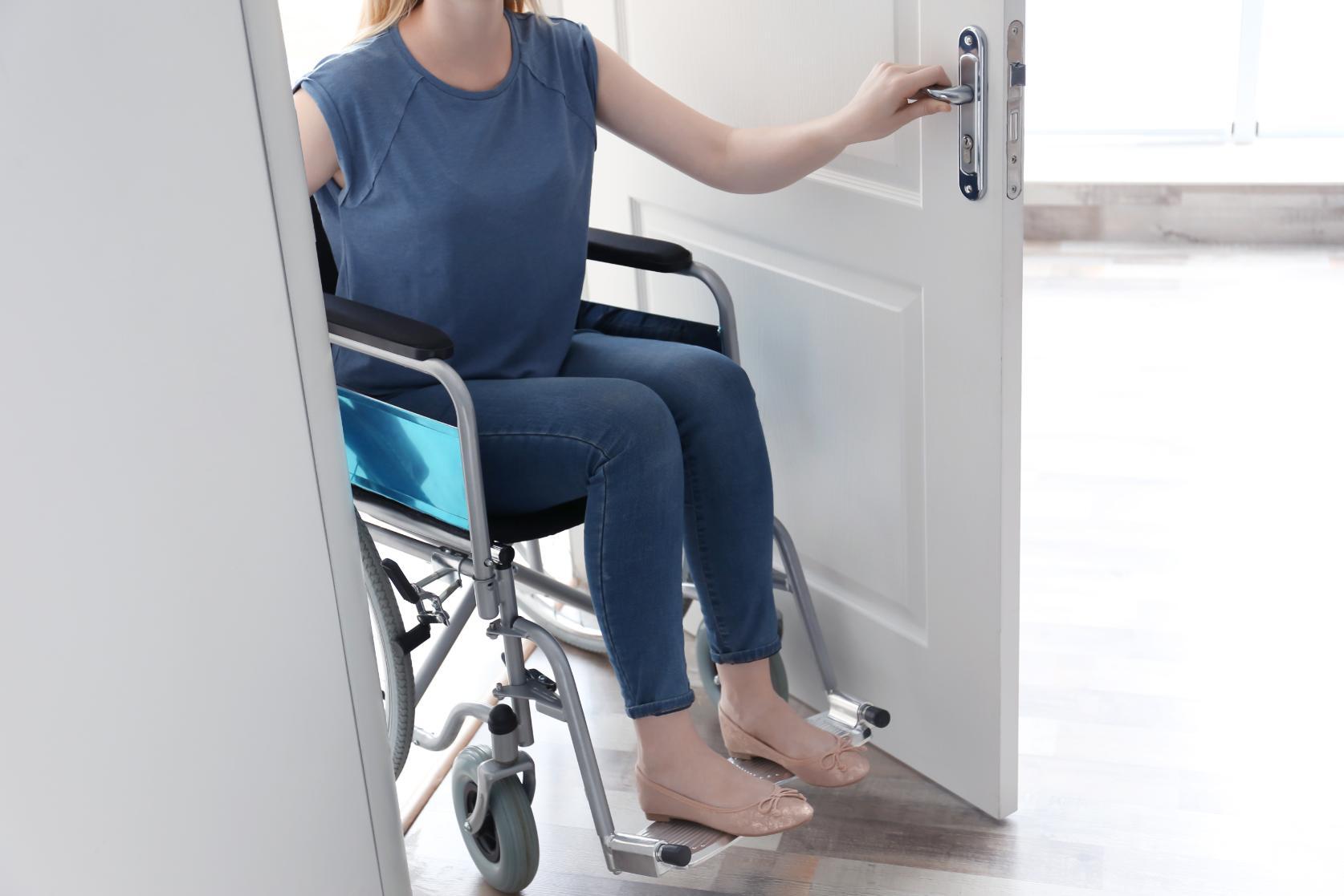 Woman in wheelchair easily entering through properly sized door meeting accessibility standards