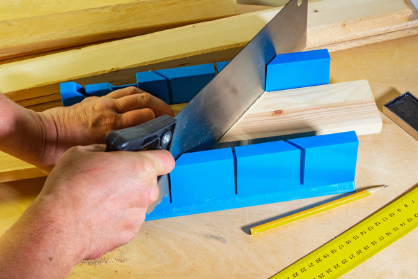 Mitre box being used to guide a hand saw for angled cuts