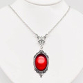 red glass amulet with a filigree silver tone border on a silver tone chain