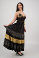 side view of a long black tiered maxi dress with spagetti straps and gold accents