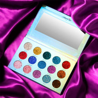 photo of an eyeshadow palette of 15 different glitter colors on a purple satin background