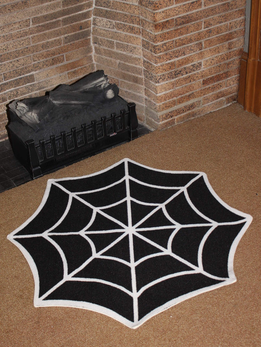 a 3' black and white spiderweb rug is shown on a brown carpeted floor in front of a tan brick fireplace